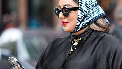 Frau läuft mit Handy in der Hand und Sonnenbrille auf der Nase über die Straße   - Foto: Getty Images / Edward Berthelot